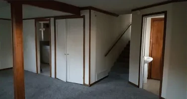 Basement with exposed post and old closets before finishing
